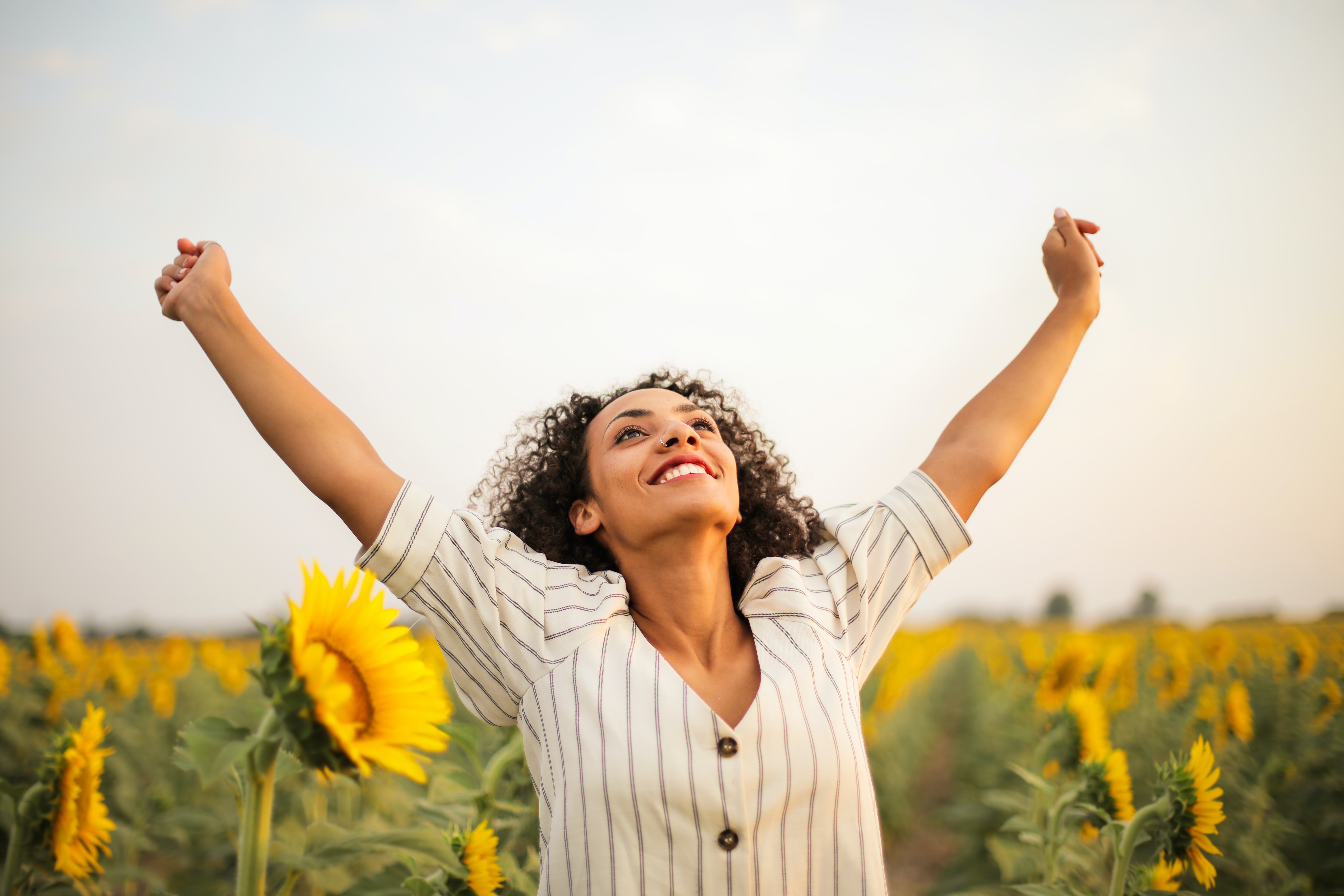 Girl in sunflowers arms up